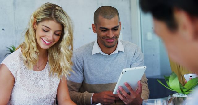 A diverse group of young adults is using digital devices while working together in an office setting. This depiction emphasizes teamwork, positive workplace atmosphere, and modern technology use. Perfect for illustrating cooperative work environments, tech usage, or business settings in presentations, advertising, and online content.