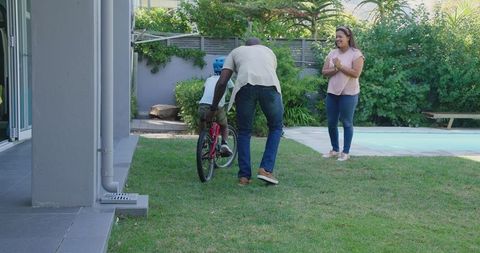 Father Teaching Son to Ride Bicycle in Backyard