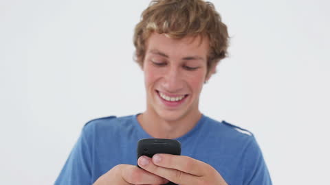 Smiling Young Man Interacting with Mobile Phone Against White Background