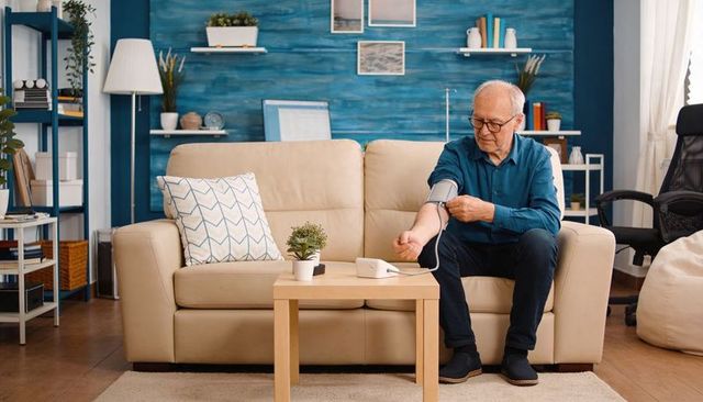 Senior man measuring blood pressure at home using digital cuff for wellness monitoring