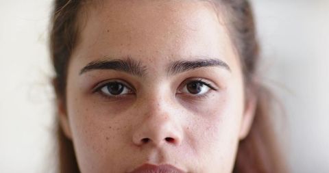 Teen girl holding steady gaze showing freckles and natural skin close-up portrait