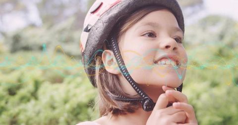 Girl fastening bike helmet and smiling while looking up with colorful waveform overlay