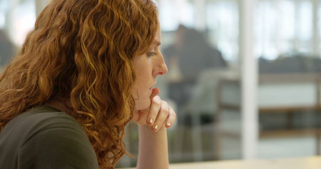 Focused Woman with Curly Red Hair Deep in Thought at Office Desk - Download Free Stock Images Pikwizard.com