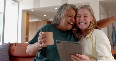 Senior Female Couple Relaxing with Tablet and Coffee at Home