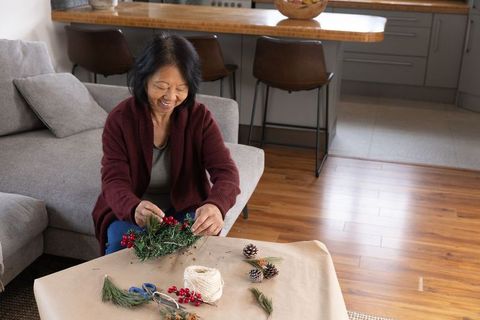 Senior Asian Woman Crafting Festive Holiday Wreath at Home
