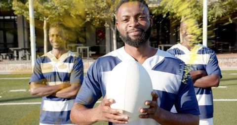 Rugby captain holding ball on sunlit field with teammates posing behind