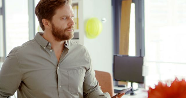 Thoughtful Bearded Man Holding Tablet in Modern Office - Download Free Stock Images Pikwizard.com