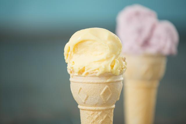Close-up of vanilla ice cream cone with strawberry ice cream cone in background