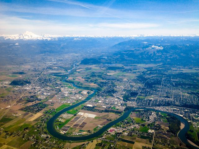 Aerial View of Scenic River Curving Through Countryside with Mountains in Distance - Download Free Stock Photos Pikwizard.com