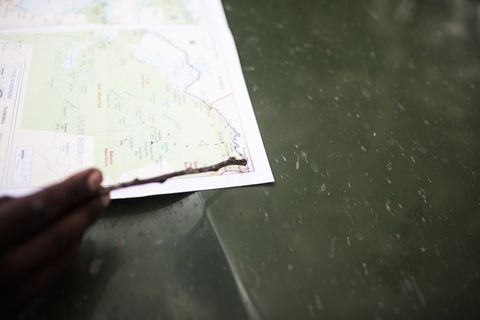 Traveler pointing map with stick on weathered green metal surface for navigation