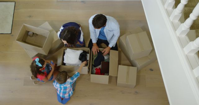 Happy caucasian parents with children unpacking cartons at new home - Download Free Stock Photos Pikwizard.com