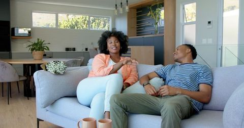 Happy Couple Relaxing on Sofa with Coffee at Home