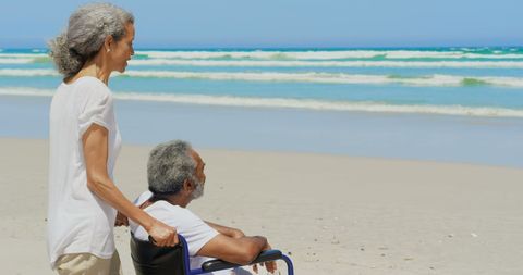 Elderly Couple Enjoying Tranquil Beach Moment With Wheelchair