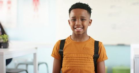 African american schoolboy smiling with backpack in classroom