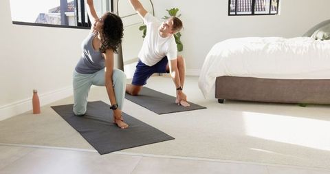 Diverse Couple Practicing Yoga in Bright and Modern Bedroom
