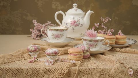 Vintage rose porcelain tea set with pastel macarons on crocheted lace tabletop
