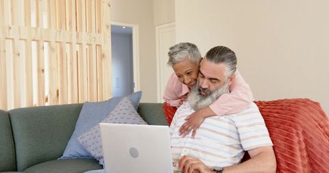 Senior Couple Relaxing on Sofa with Laptop at Home