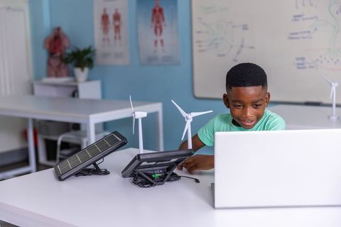African american boy exploring renewable energy with solar and wind kits at school
