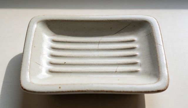Vintage white ceramic soap dish with six raised ridges, glaze craquelure and patina