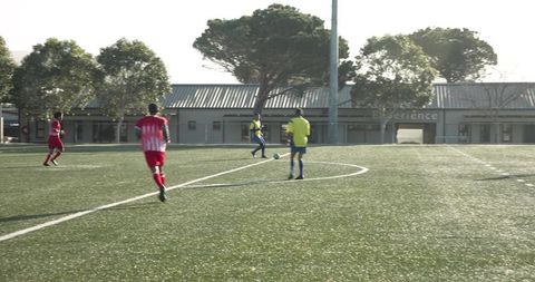 Young Soccer Player Dribbling Ball on Outdoor Field with Team Mates