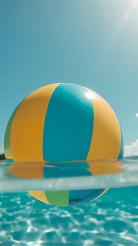 Vertical summer video of colorful beach ball bobbing and rotating on turquoise sea