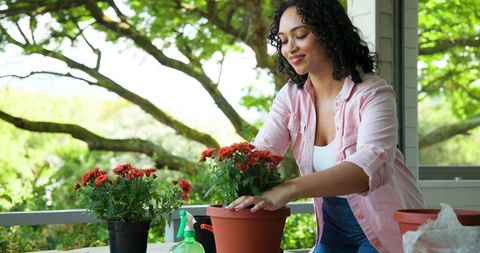 Woman enjoying gardening on porch with red flowers, creates calm outdoor space