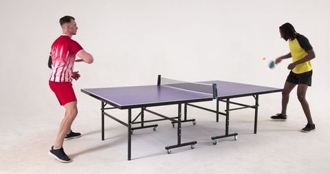 Diverse friends playing intense table tennis match