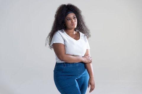 African american woman standing contemplative pose wearing white top and blue denim jeans