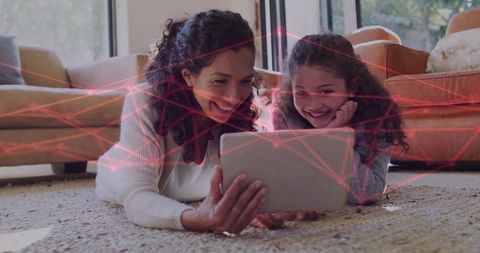 Mother daughter sharing tablet on living room rug with red network overlay