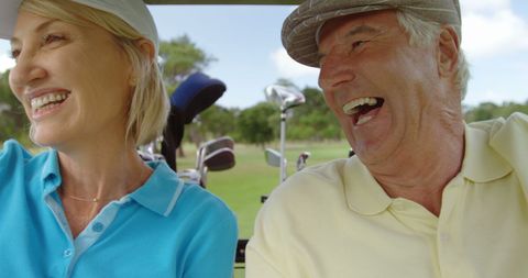 Happy senior golfers enjoying ride on golf course