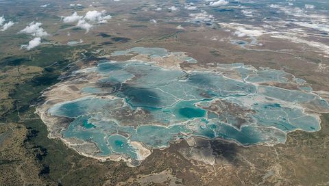 Aerial view of salt flats with turquoise lakes on arid plain