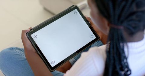 African teen holding tablet with blank screen on lap for education technology mockup
