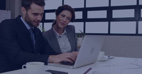 Business Professionals Analyzing Data on Laptop in Modern Workspace