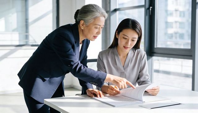 Senior mentor guiding junior professional reviewing report showing leadership in modern office