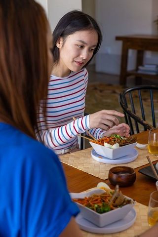 Female friends enjoying casual dining with noodle salad