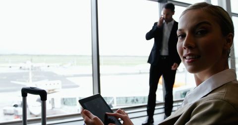 Businesswoman Using Tablet at Airport with Colleague