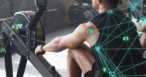 Athletic man using rowing machine in modern gym