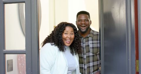 Welcoming Couple Greeting Guests at Home Entrance