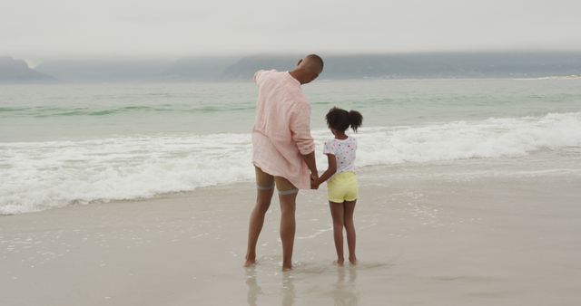 Happy african american father and daughter holding hands on beach. Lifestyle, fatherhood, childhood, summer, leisure and vacation, unaltered.