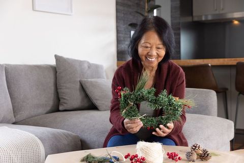 Senior Asian Woman Crafting Festive Wreath Indoors