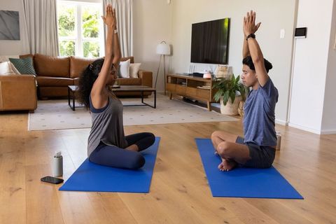 African couple practicing overhead yoga on blue mats in bright minimalist living room