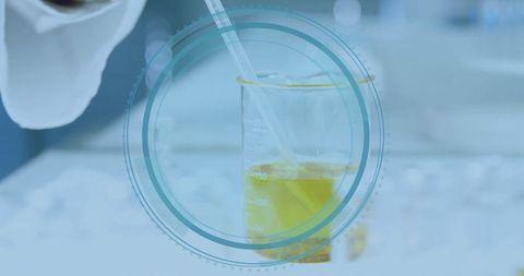 Scientist pipetting yellow liquid into beaker in high-tech lab