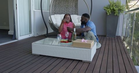 Happy Couple Relaxing with Drinks on Cozy Outdoor Patio