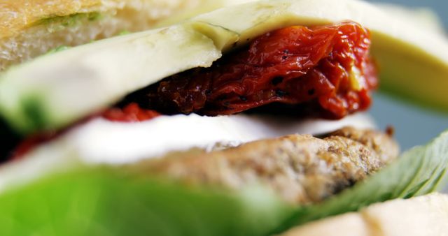 A close-up view showcases a delicious sandwich filled with sun-dried tomatoes, avocado, and meat, with copy space. Fresh ingredients and vibrant colors invite a sensory experience of taste and texture.