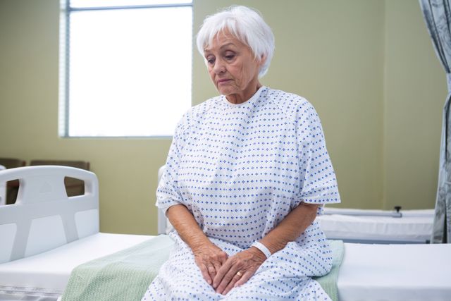 Worried senior patient sitting on bed in hospital