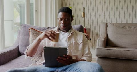 Man relaxing at home with tablet and coffee