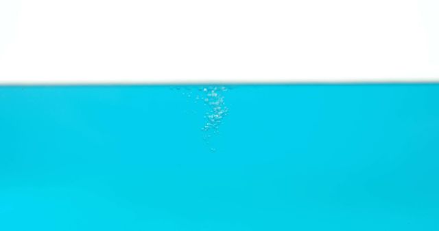 Bubbles rise in clear blue water against a white and blue background, with copy space. It's a simple yet refreshing visual that could be associated with purity, cleanliness, or aquatic environments.