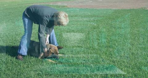 Senior woman training dog in sunny park