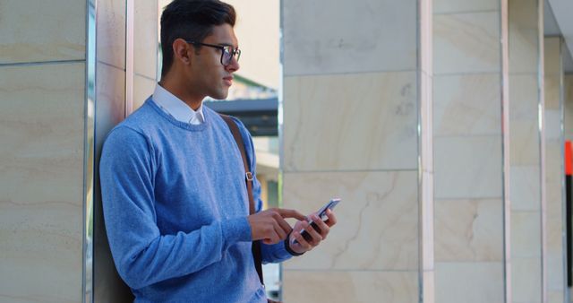 Young Man in Blue Sweater Using Smartphone Outside Office Building - Download Free Stock Images Pikwizard.com