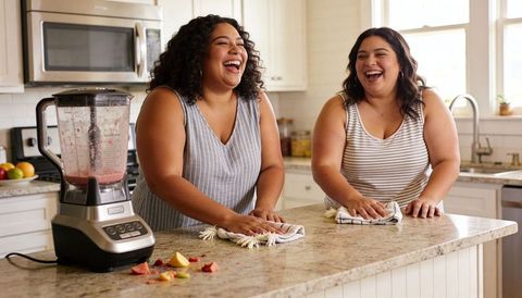 Laughing friends wiping granite kitchen island together, casual morning tidy and bonding